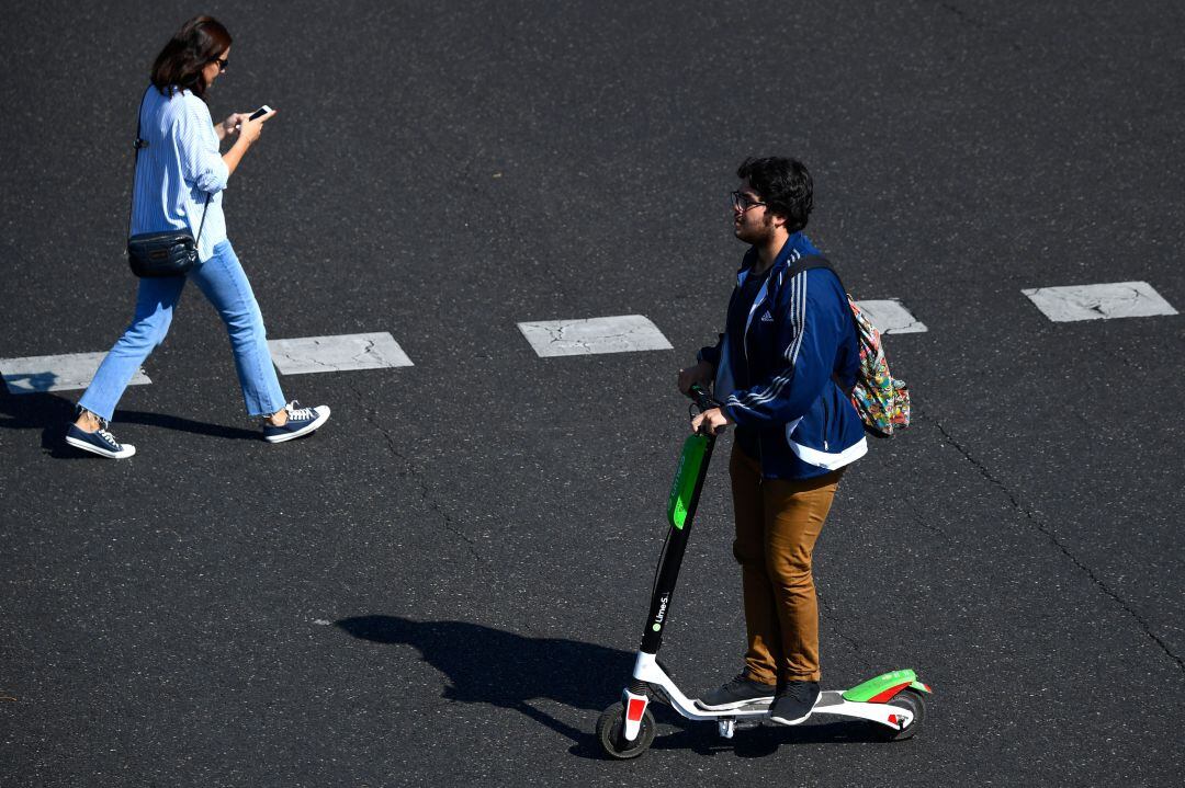 Un usuario de patinete cruza la calle en Madrid.