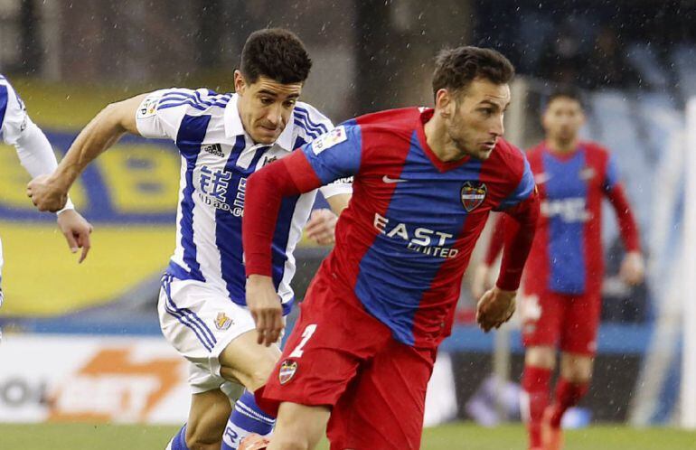 El defensa del Levante Iván López (d) con el balón ante el defensa de la Real Sociedad Yuri Berchiche 