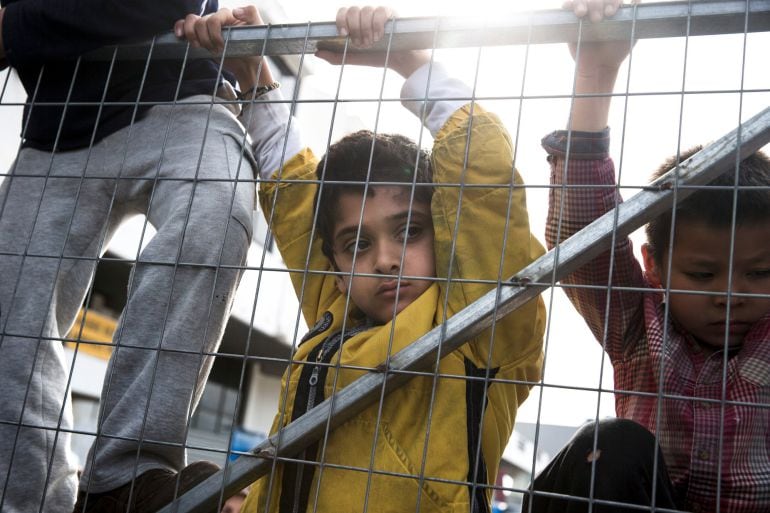 Niños escalan la entrada del campo de refugiados en el aeropuerto de Hellenikon en Grecia