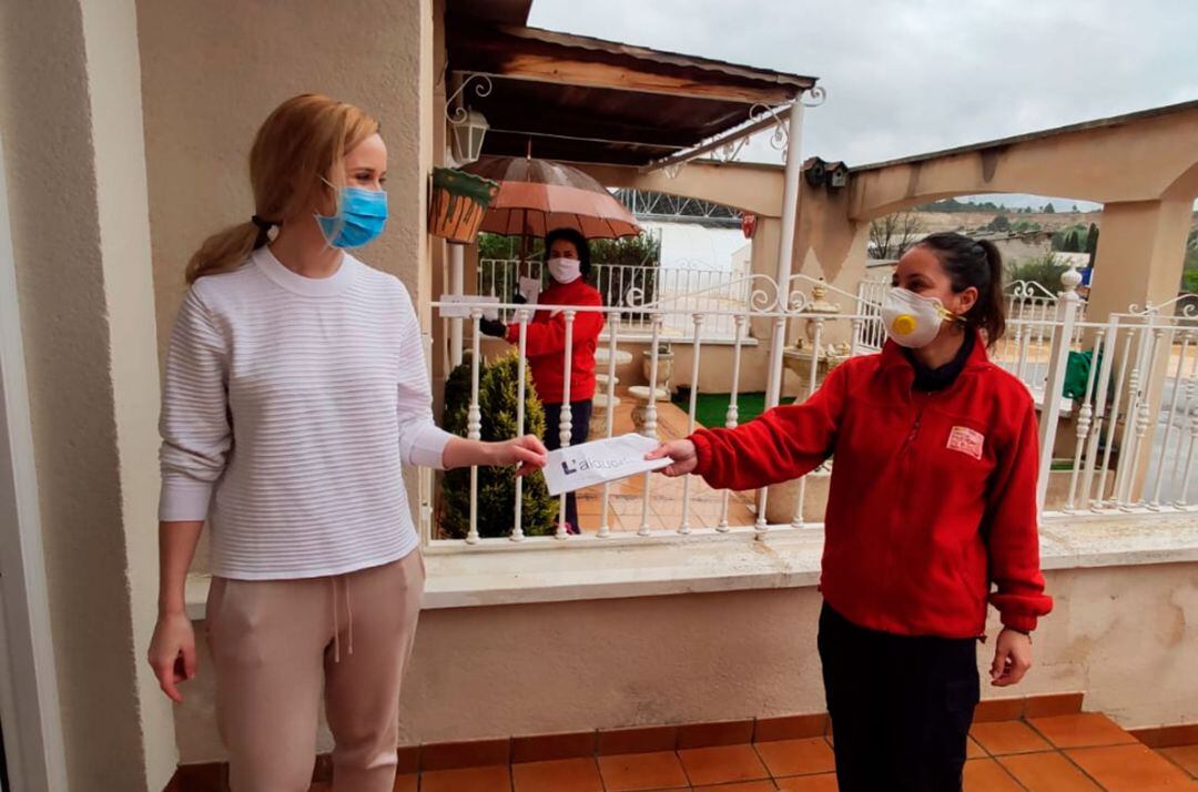 Un momento en el que una voluntaria entrega una mascarilla a una vecina de L'Alqueria d'Asnar