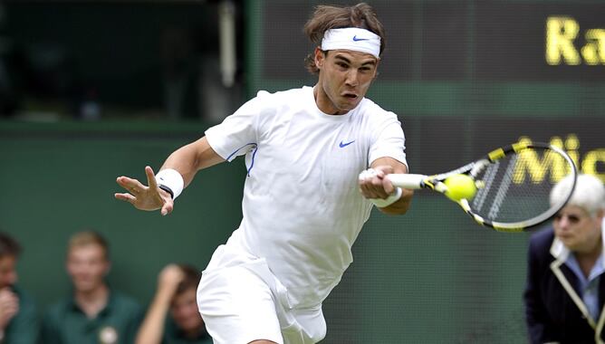 El tenista español Rafael Nadal devuelve la bola al estadounidense Michael Russel durante su partido de primera ronda del torneo de Wimbledon