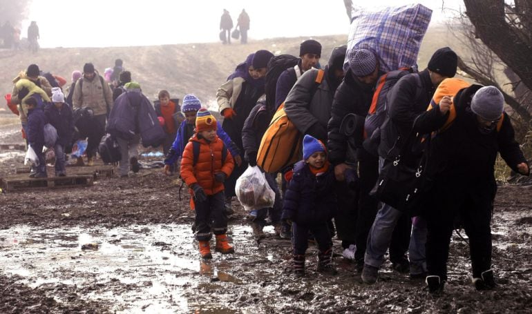 Un grupo de migrantes caminan para ingresar a un campamento temporal en Presevo (Serbia) 