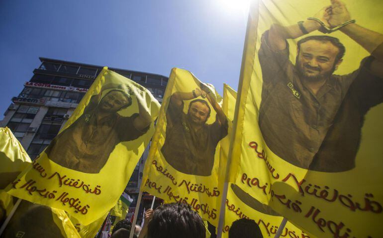 Palestinos sostienen banderas con la imagen del líder del partido nacionalista Al Fatah, Marwan Barguti, que cumple en prisión cinco cadenas perpetuas por ataques durante la Segunda Intifada, en la ciudad cisjordana de Ramala, hoy, 17 de abril de 2017. Al