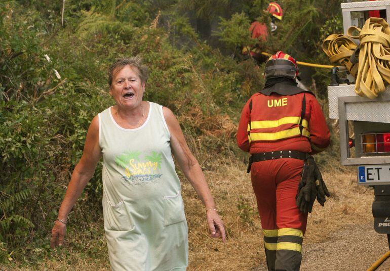 Una vecina y varios efectivos de la UME en la zona de Sela, en el incendio forestal de Arbo (Pontevedra) en el que se ha decretado la Situación 2 por la cercanía del fuego a núcleos de población