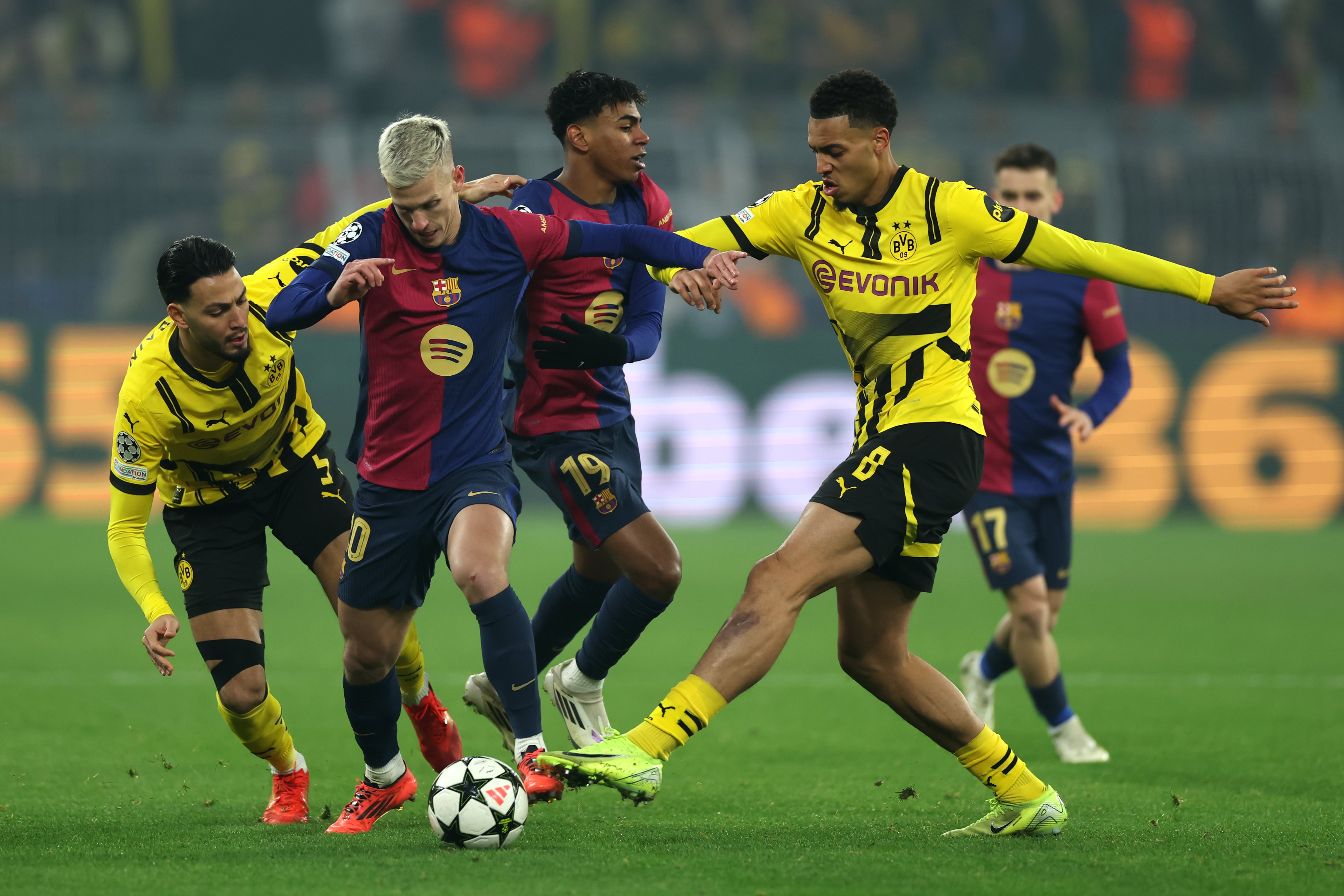 DORTMUND, GERMANY - DECEMBER 11: Dani Olmo of FC Barcelona is challenged by Ramy Bensebaini and Felix Nmecha of Borussia Dortmund during the UEFA Champions League 2024/25 League Phase MD6 match between Borussia Dortmund and FC Barcelona at BVB Stadion Dortmund on December 11, 2024 in Dortmund, Germany. (Photo by Lars Baron/Getty Images)