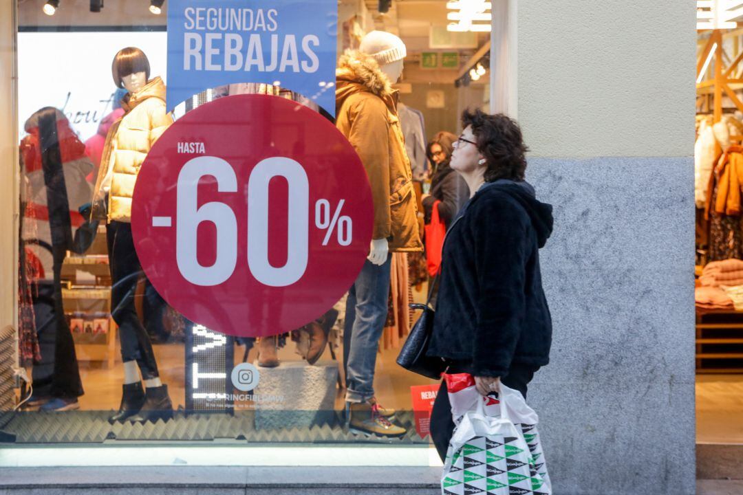 Una mujer pasea junto a una tienda de moda en la que se ofertan las segundas rebajas 