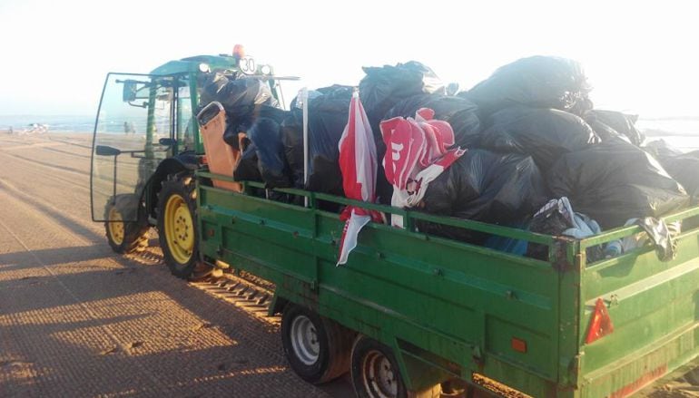 Servicios de limpieza retirando las sombrillas y sillas abandonadas en primera línea de playa