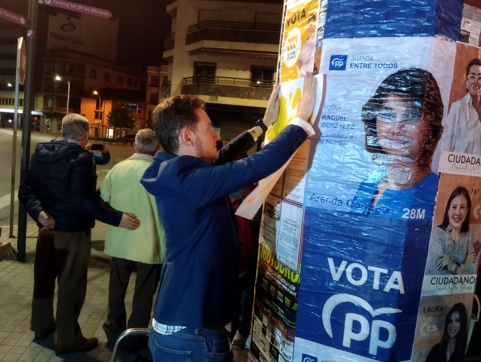 Antonio Linaje pega el cartel de Sentir Aranda en el inicio de campaña junto al cartel del PP