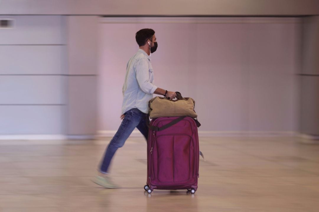 Un hombre camina con su equipaje en la terminal T1 del Aeropuerto de Madrid - Barajas Adolfo Suárez.