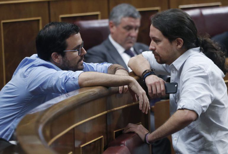 El líder de Podemos, Pablo Iglesias (d), conversa con el diputado de Unidos Podemos Alberto Garzón, durante la sesión de la tarde de la segunda jornada del debate de investidura del candidato del PP, Mariano Rajoy