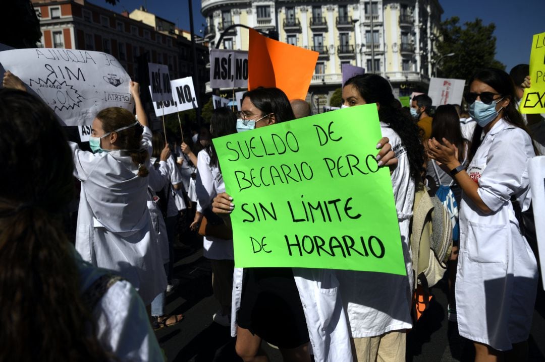 Una sanitaria sostiene un cartel en el que se lee &#039;Sueldo de becario pero sin límite de horario&#039; durante una manifestación MIR