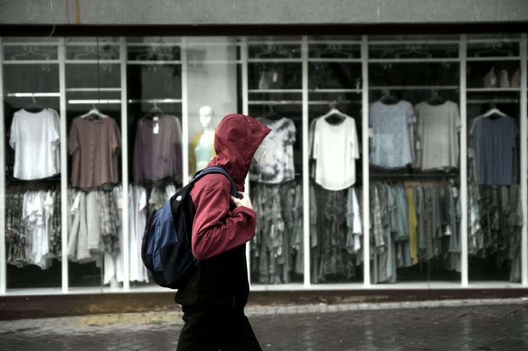 Archivo - Un hombre pasea frente a una tienda 