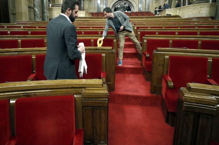 Jordi Cabrafiga, asesor del partido JXCat y el diputado de ERC, Ferran Civit  recogen del hemiciclo los cuatro lazos colocados como homenaje a los políticos del partido encarcelados en el Parlament de Cataluña. 