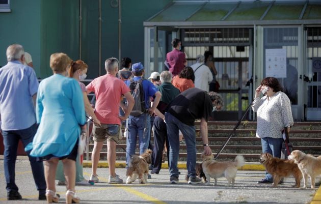 Varias personas aguardan en la fila para votar, este domingo en un colegio electoral en Monte Alto, A Coruña