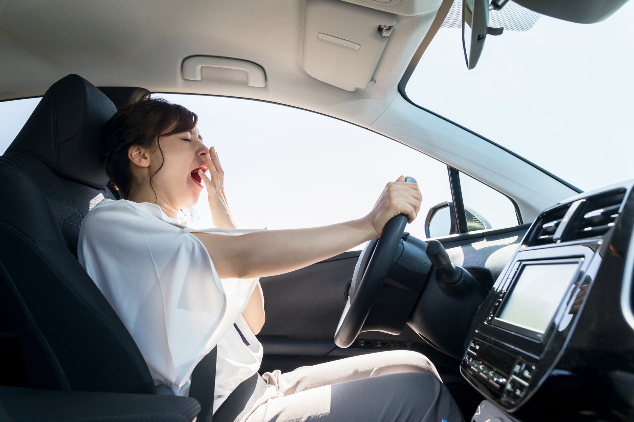 Una mujer bosteza al volante.