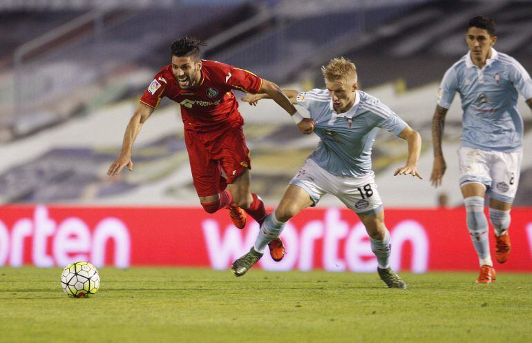 El centrocampista del Getafe, Ángel Lafita, cae ante la entrada del jugador danés del Celta de Vigo, Daniel Wass.