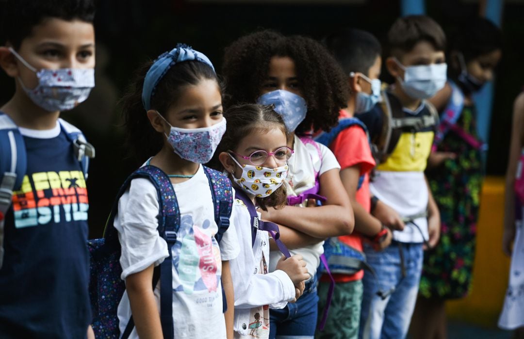 Niños hacen cola en el patio del colegio para entrar a clase. 