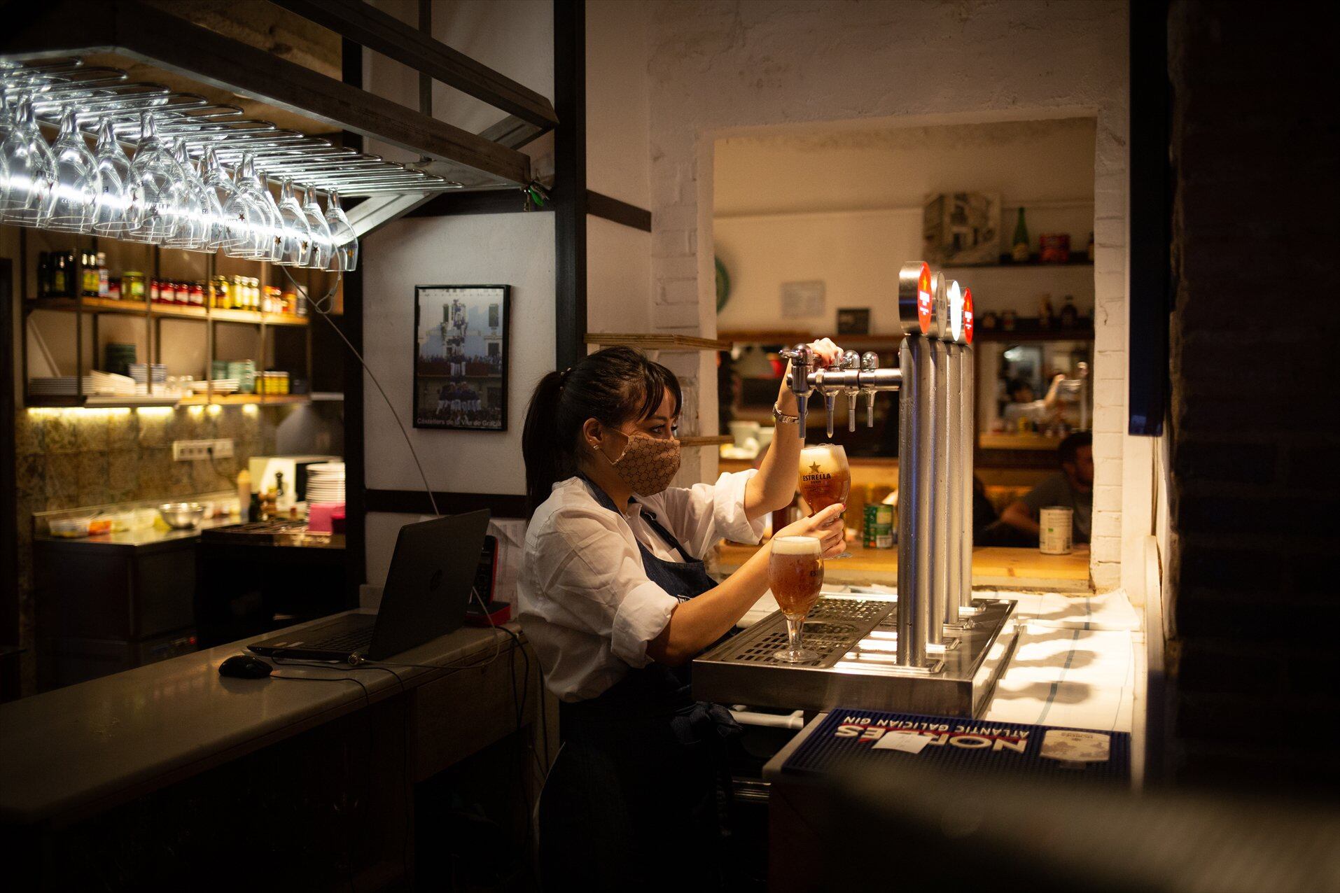 Una camarera sirve una cerveza en el interior de un bar en una calle céntrica de Barcelona