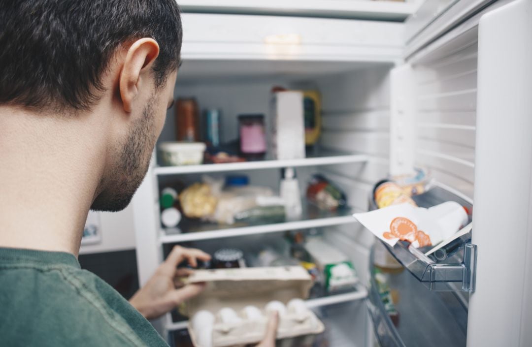 Un hombre manipula unos huevos antes de meterlos en la nevera.