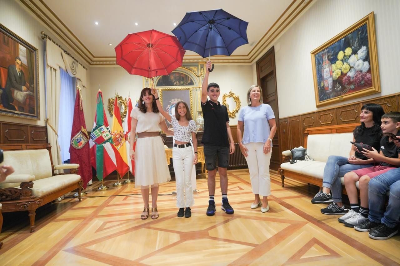 Alazne Rubio y Ioritz Esperanza sostienen los paraguas de Edurne y Celedón Txiki en la sala de recepciones del Ayuntamiento de Vitoria con la alcaldesa Maider Etxebarria y la concejala de cultura Sonia Díaz de Corcuera