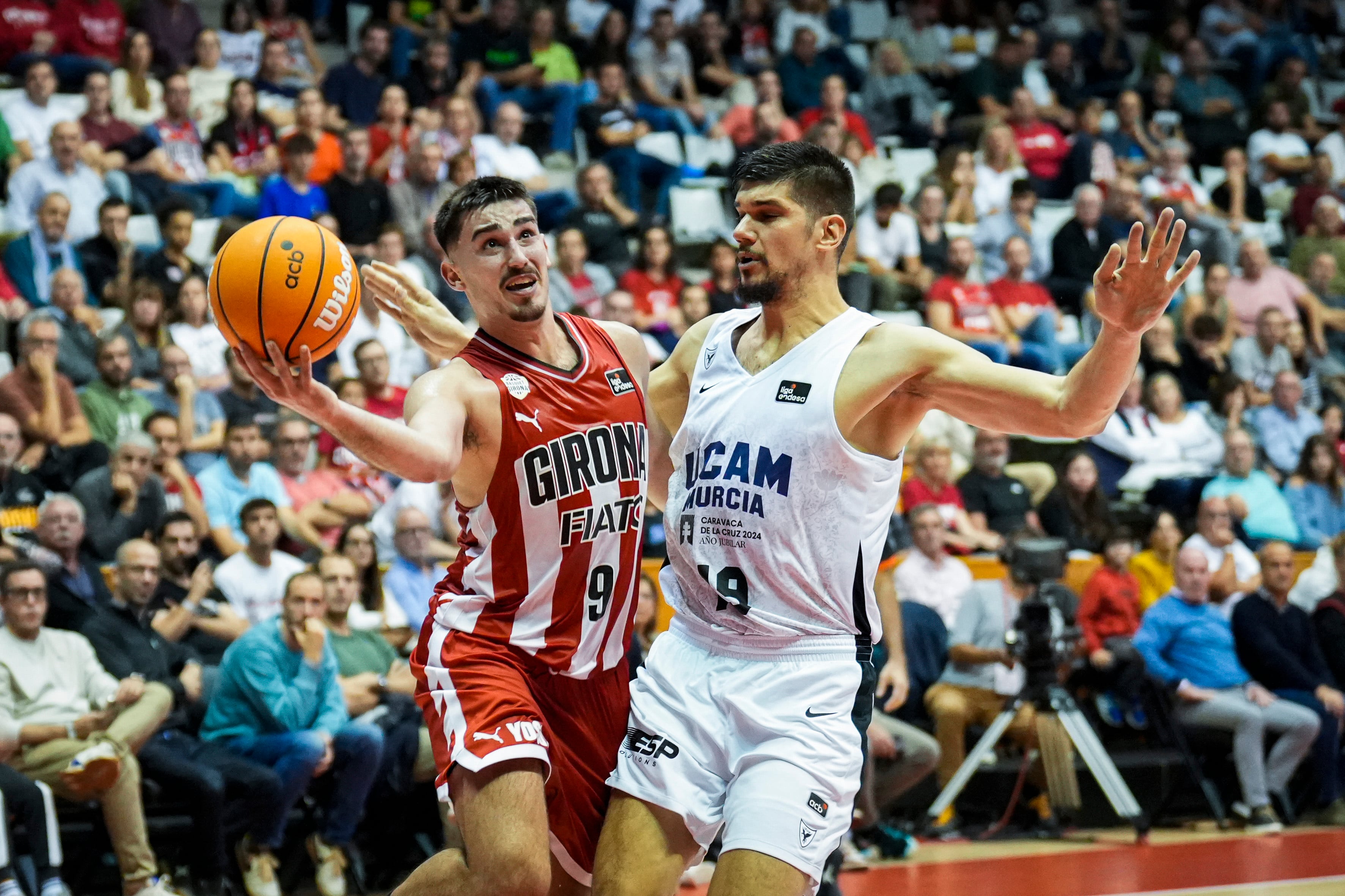 GIRONA, 26/10/2024.- El base del Girona Guillem Ferrando (i) lucha con el montenegrino Marko Todorovic, de UCAM Murcia, durante el partido de la Liga Endesa entre el Basquet Girona y UCAM Murcia, este sábado en el pabellón de Fontajau. EFE/David Borrat.
