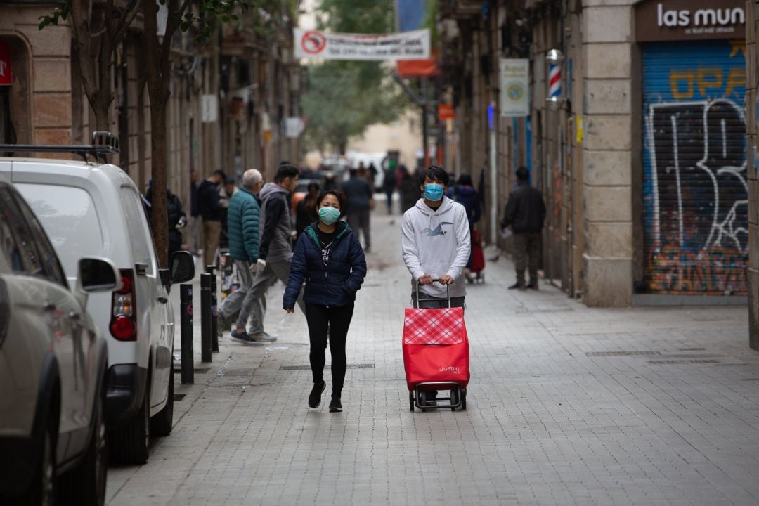 Dos personas protegidas con mascarillas durante el segundo día laborable del estado de alarma por el coronavirus, en Barcelona