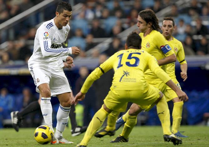 El delantero portugués del Real Madrid Cristiano Ronaldo (i) con el balón ante los jugadores del Villarreal, José Manuel Catalá (c) y el argentino Gonzalo Rodríguez (2d), durante el partido, correspondiente a la decimoctava jornada de Liga de Primera Divi