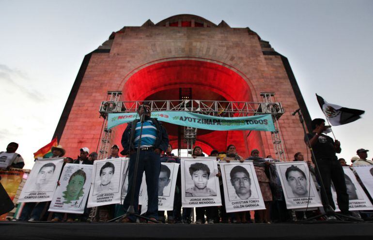 Felipe de la Cruz, the father of one of the 43 missing students from the Isidro Burgos rural teachers college, speaks to a crowd in front of other relatives holding posters of their missing loved ones, during a protest at the Revolution Monument in Mexico