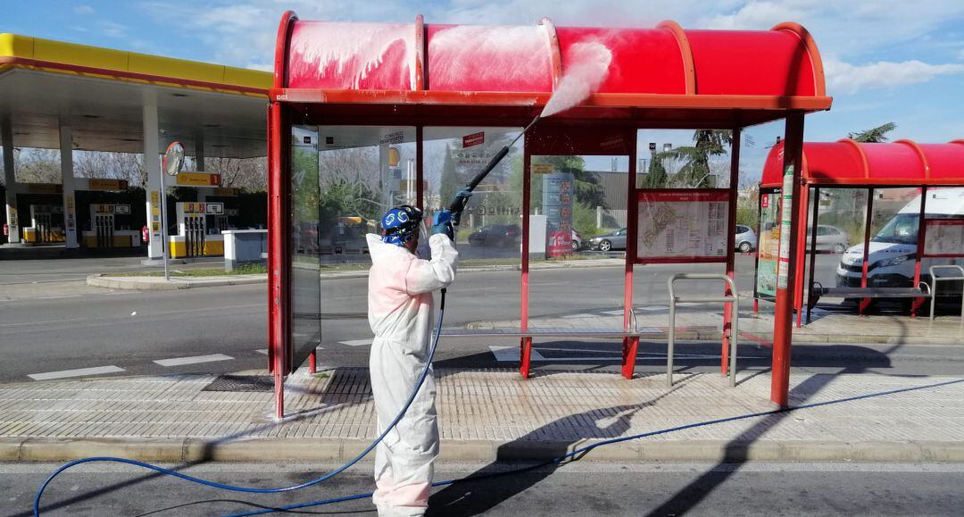 Un operario desinfecta una marquesina de autobús en Getafe.