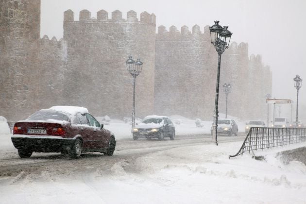 Varios vehículos circulan por una carretera próxima a la muralla de Ávila.