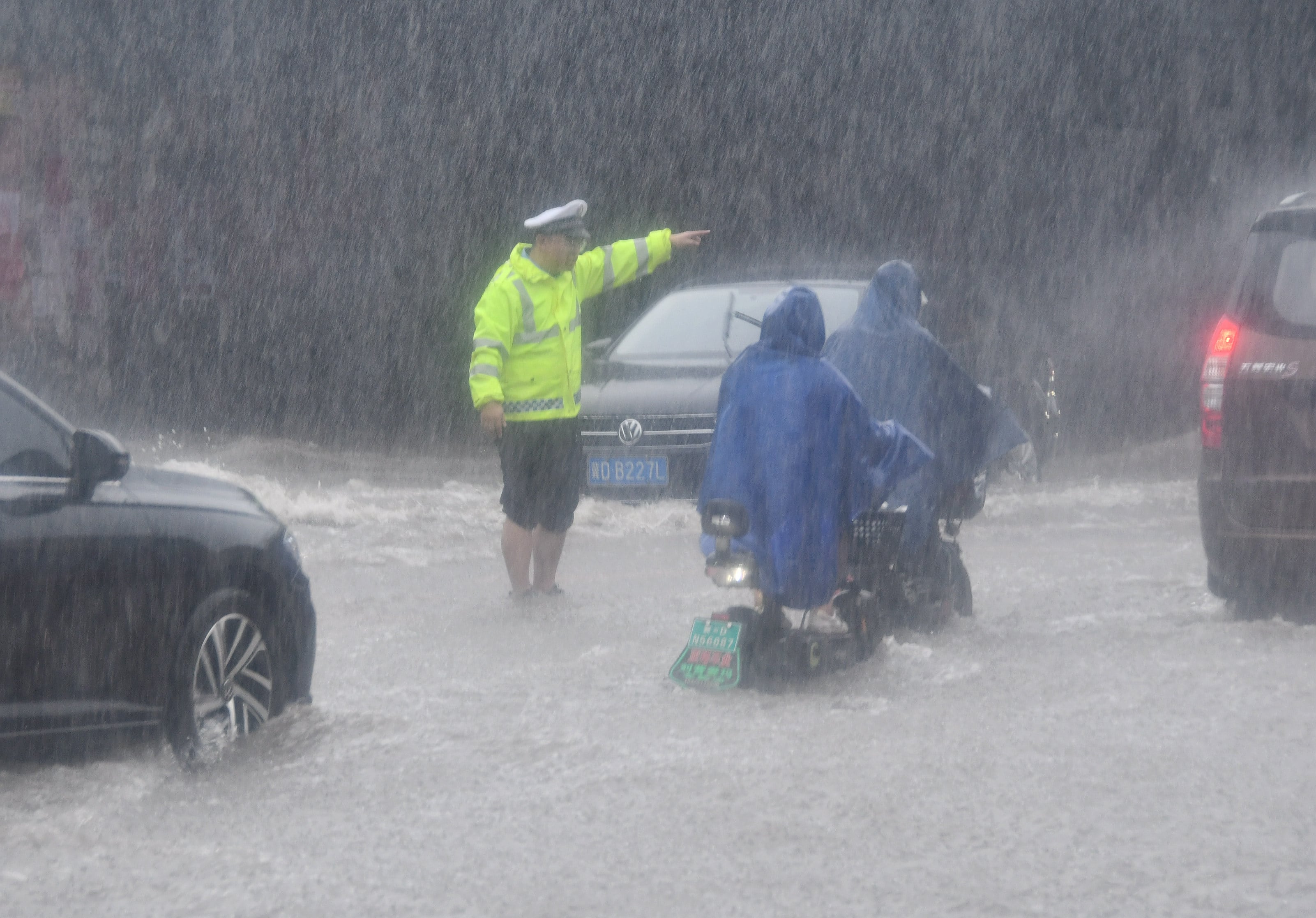 Un agente de tráfico guía a los conductores bajo la lluvia torrencial en China