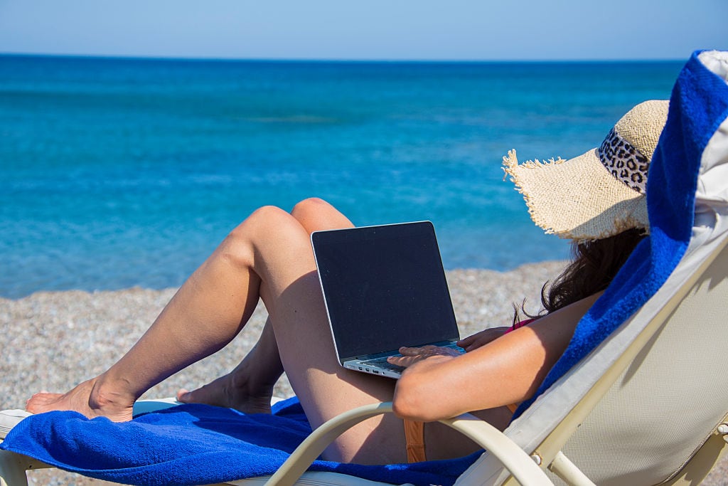 Una mujer con un ordenador, en la playa.