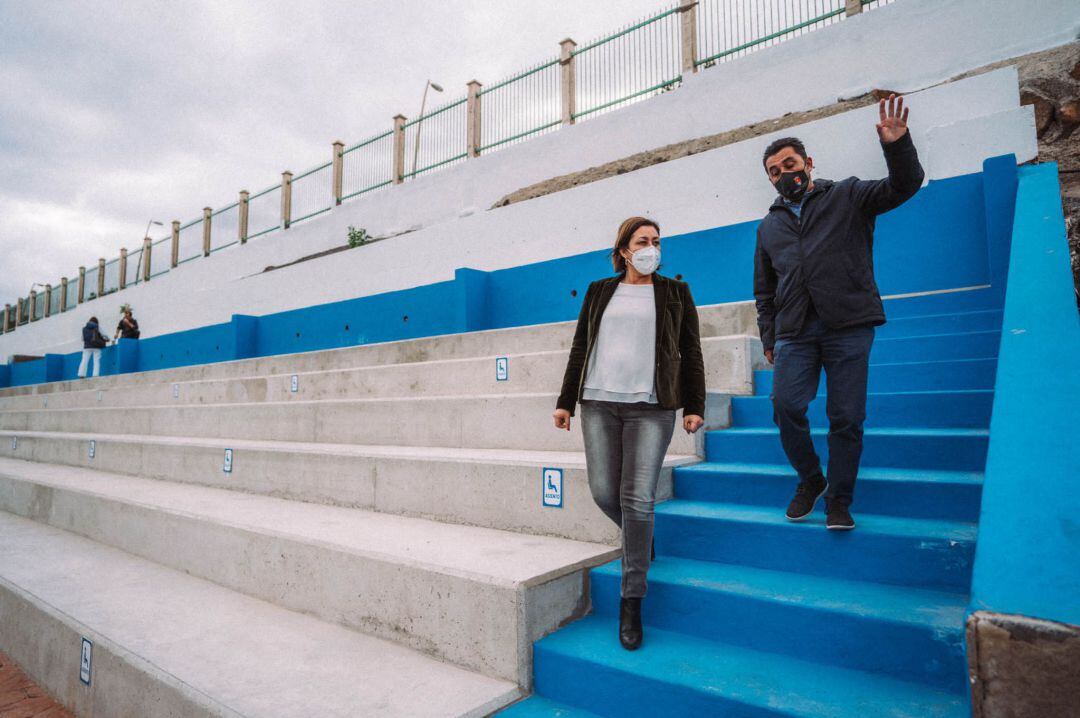 La alcaldesa de Arrecife, Ástrid Pérez, y el concejal de Deportes, Roy González, en las gradas del campo de fútbol de San Francisco Javier de Arrecife.