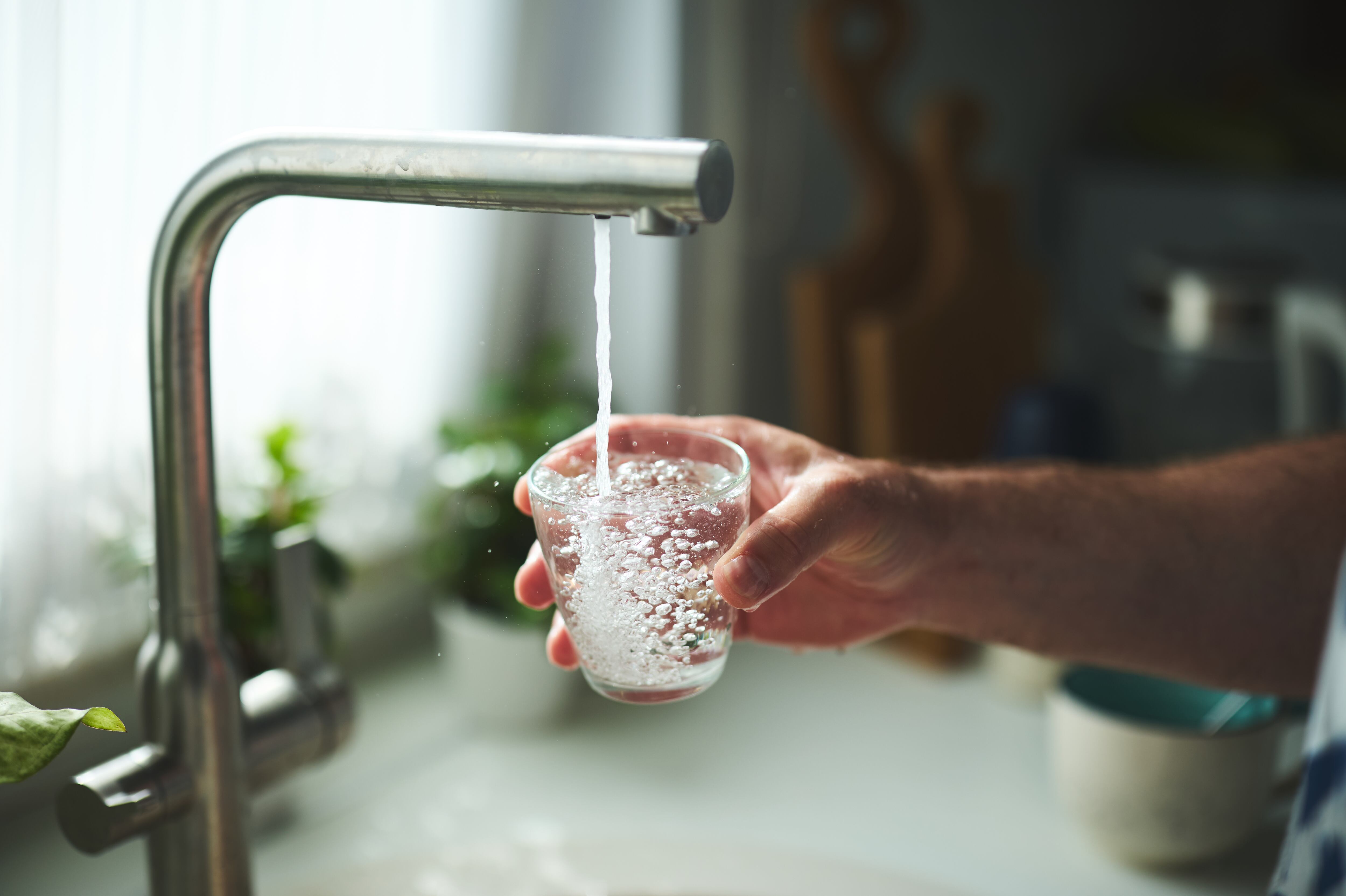 Una persona cogiendo agua del grifo.