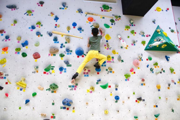 Niño ascendiendo por un rocódromo