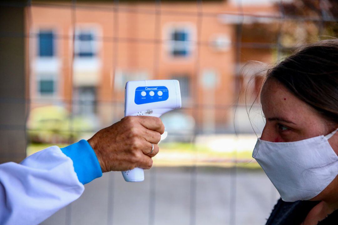 Un sanitario le toma la temperatura a una mujer antes de realizarle un test de antígenos, en el Centro Cultural Lope de Vega, en la Zona Básica de Salud (ZBS) de Puente de Vallecas, en Madrid.