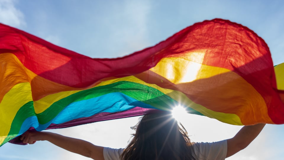 Una persona ondea una bandera arco iris