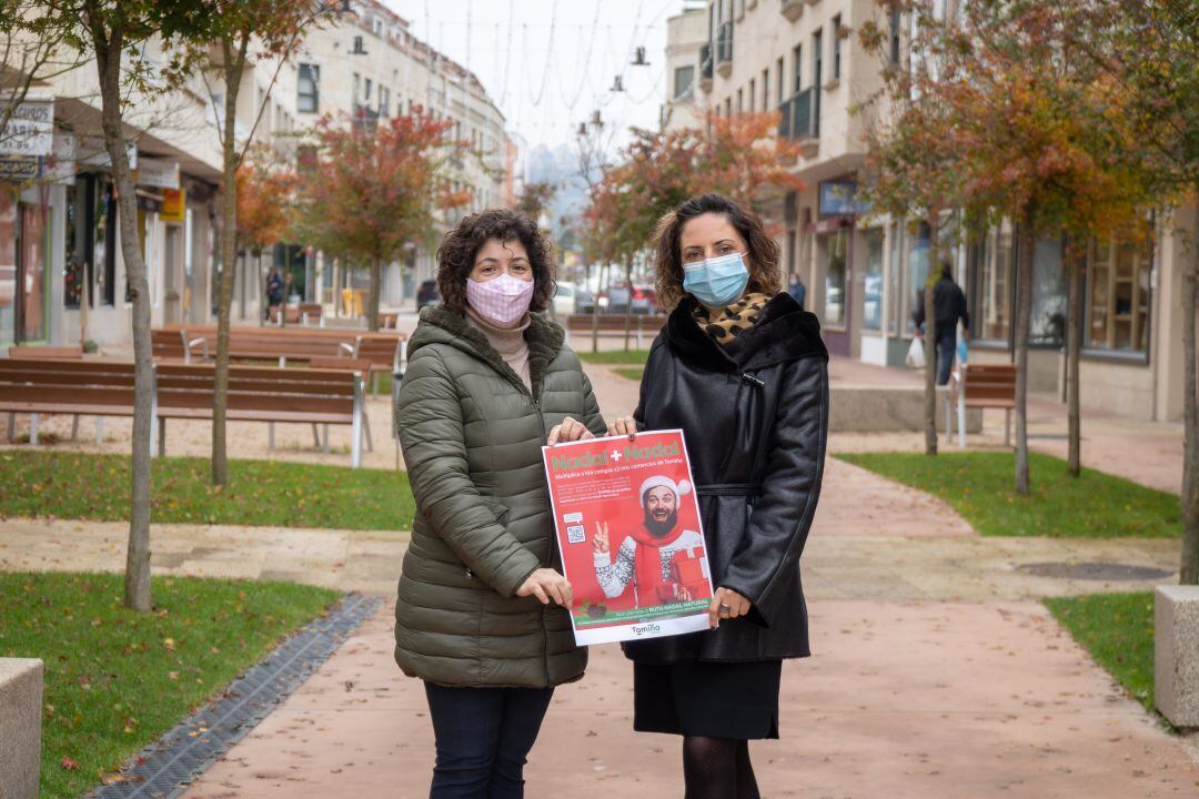 La alcaldesa de Tomiño, Sandra González (derecha), junto a la técnica de comercio del Concello sujetando el cartel de la campaña &quot;Nadal + Nadal&quot;.