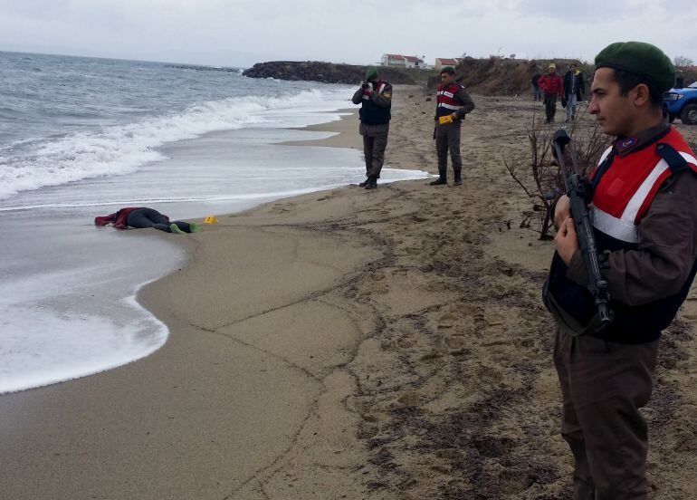 Un gendarme turco vigila el trabajo de los forenses en el lugar en el que han llegado los cadáveres del naufragio de una barca con refugiados que se dirigían a la isla griega de Lesbos. 