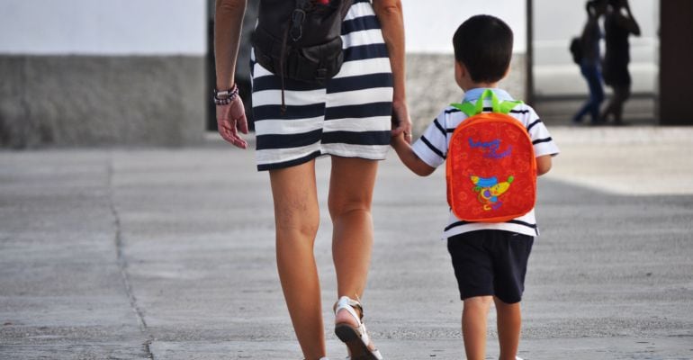 Una madre camina al colegio con su hijo de la mano.