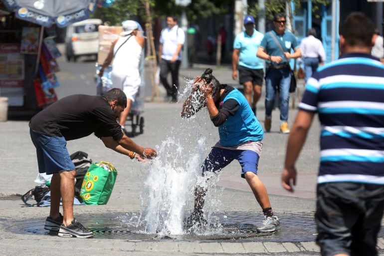 Un grupo de personas se refrescan en las calles de Santiago de Chile que está registrando estos días una serie de de temperaturas extremas. 