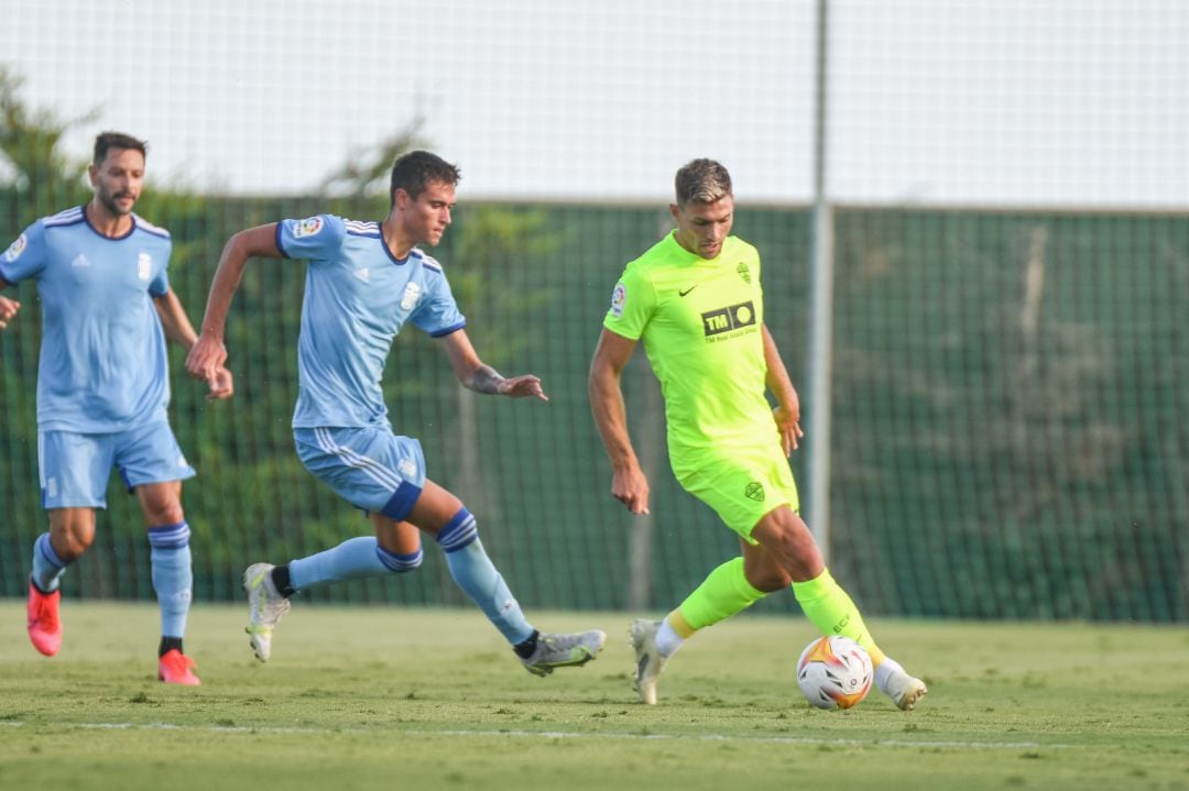 El delantero del Elche Lucas Boyé controla el balón ante dos rivales 