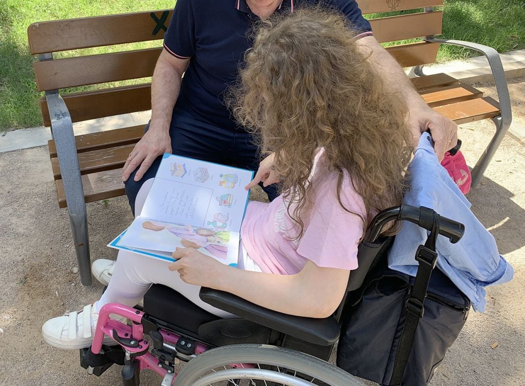 Un niña en silla de ruedas junto a su padre.