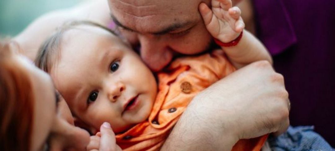 Dos padres acarician a su bebé.