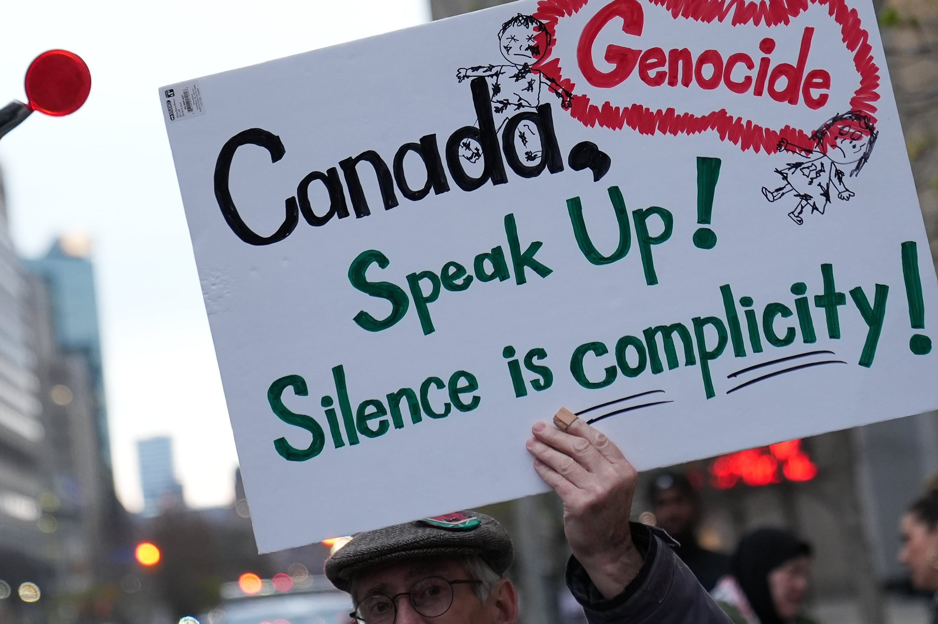 Un manifestante sostiene una pancarta con el lema &quot;Canadá, ¡alza la voz!, ¡el silencio es complicidad!&quot; en una marcha propalestina en Toronto
