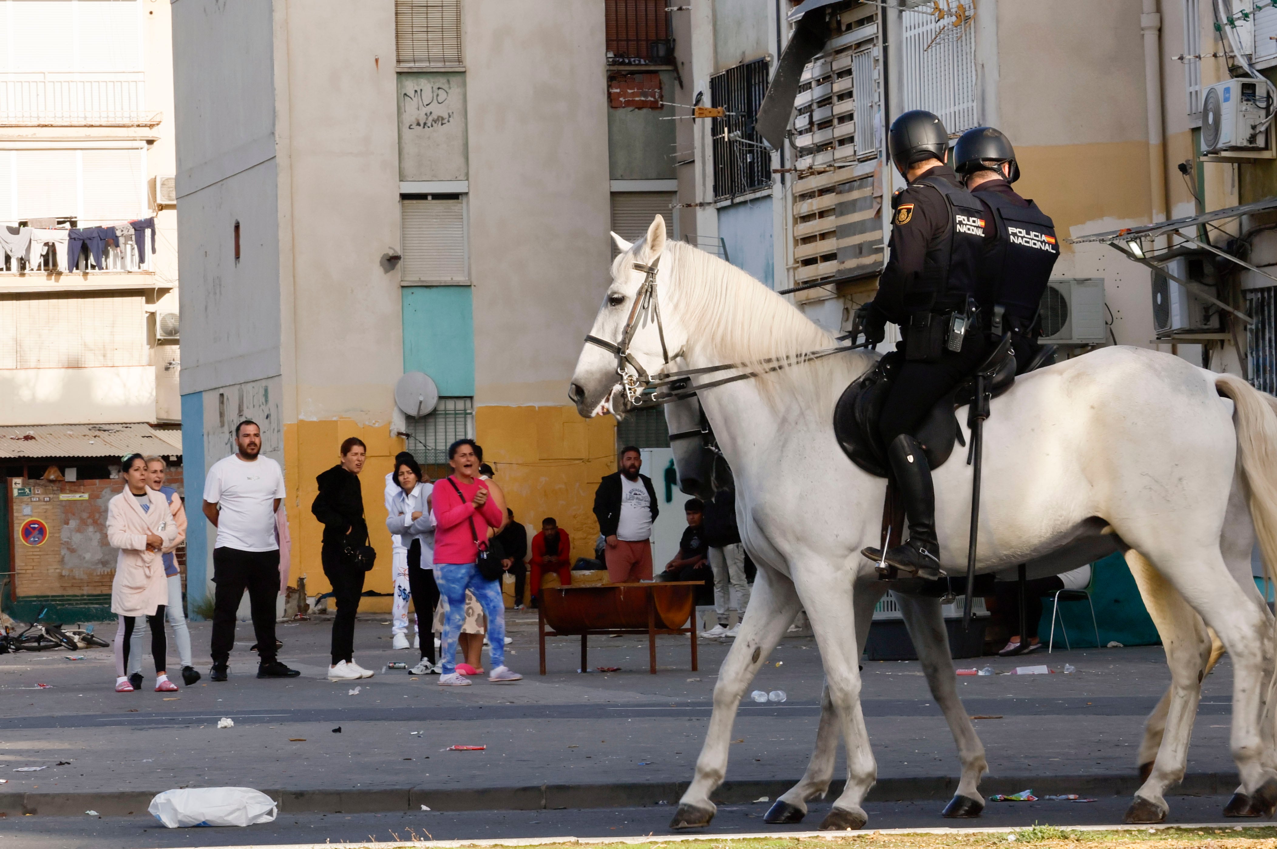 Los vecinos de las Tres Mil Viviendas observan la redada de la Policía Nacional que ha vuelto a desplegarse este viernes en esta barriada de Sevilla