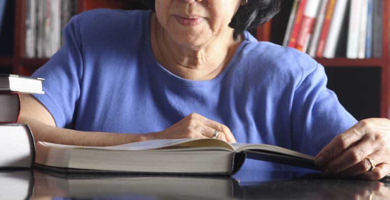 Una mujer ojea un libro en una biblioteca.