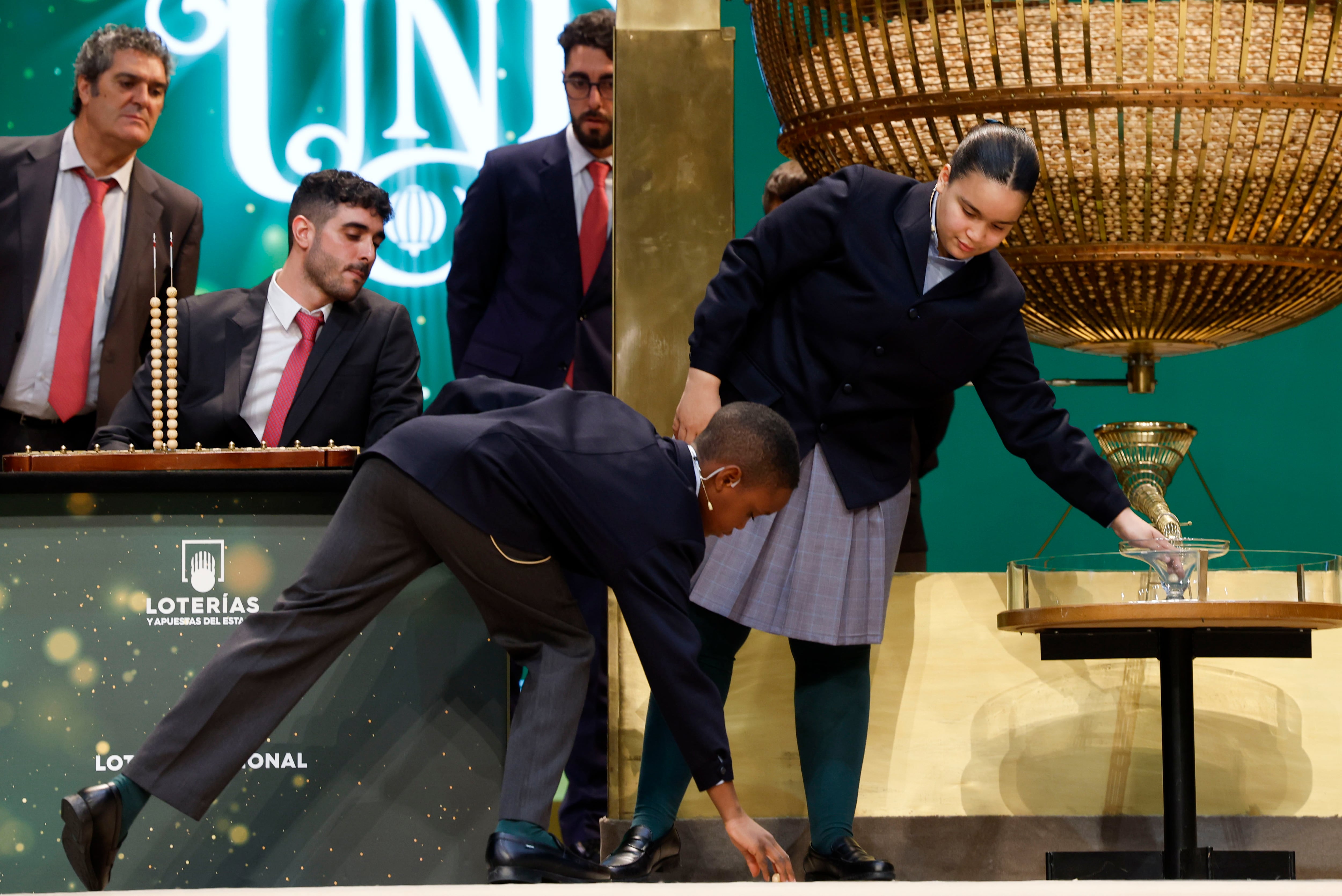 MADRID, 22/12/2023.- Uno de los niños de San Ildefonso recoge la bola que se le ha caído durante el sorteo extraordinario de Navidad de la Lotería Nacional este viernes en el Teatro Real de Madrid. EFE/ J.J. Guillén
