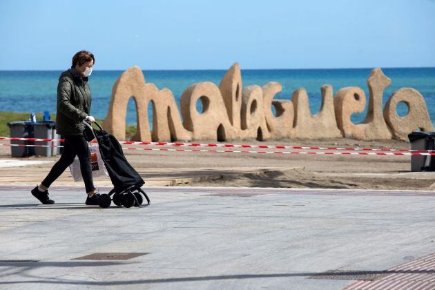 Una mujer camina delante de unos de los accesos cerrados a la playa de La Malagueta de la capital durante la séptima jornada de confinamiento tras decretarse el Estado de Alarma por el coronavirus