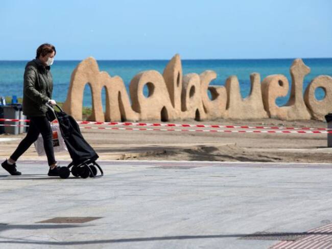 Una mujer camina delante de unos de los accesos cerrados a la playa de La Malagueta de la capital durante la séptima jornada de confinamiento tras decretarse el Estado de Alarma por el coronavirus
